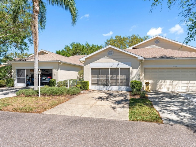 ranch-style home featuring stucco siding, roof with shingles, and a sunroom