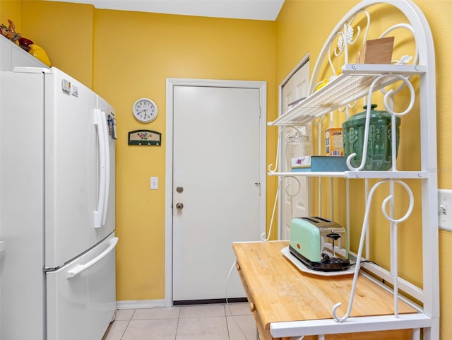 kitchen with baseboards, tile patterned flooring, and freestanding refrigerator