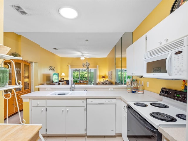 kitchen with visible vents, light countertops, a peninsula, white appliances, and a sink