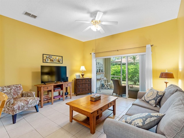 living room featuring a textured ceiling, light tile patterned floors, visible vents, and ceiling fan