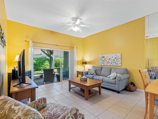 living area with light tile patterned floors, a ceiling fan, and a textured ceiling