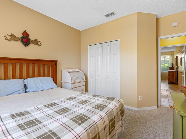 bedroom featuring visible vents, light carpet, a textured ceiling, a closet, and baseboards