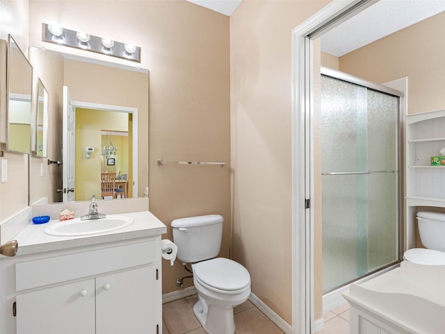 bathroom featuring vanity, baseboards, tile patterned flooring, a shower stall, and toilet