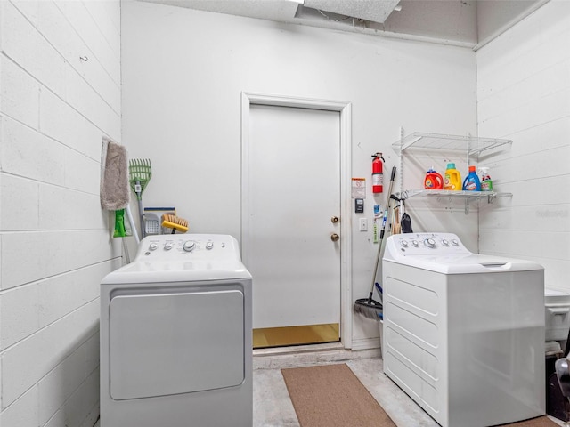 laundry area with concrete block wall, laundry area, and washing machine and clothes dryer