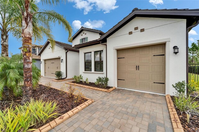 view of front of property featuring stucco siding, an attached garage, and driveway
