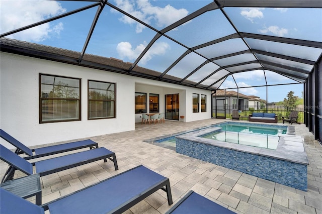 view of pool featuring glass enclosure, fence, a pool with connected hot tub, and a patio area
