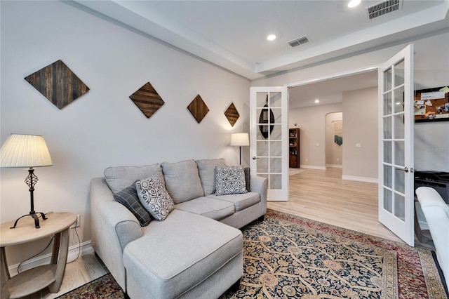 living room featuring french doors, visible vents, and wood finished floors