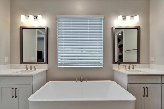 bathroom featuring a sink, a freestanding tub, and two vanities