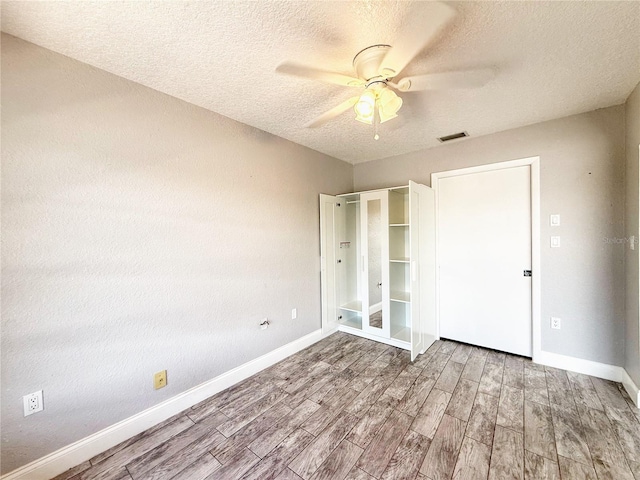 unfurnished bedroom with baseboards, visible vents, wood finished floors, and a textured ceiling