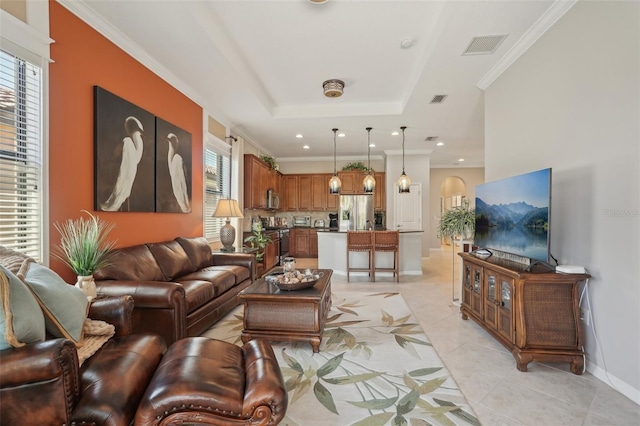 living area with visible vents, crown molding, baseboards, a tray ceiling, and light tile patterned floors