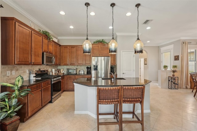kitchen featuring tasteful backsplash, a center island with sink, visible vents, appliances with stainless steel finishes, and brown cabinets