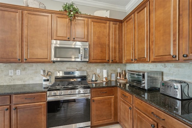 kitchen featuring dark stone countertops, appliances with stainless steel finishes, brown cabinetry, and crown molding