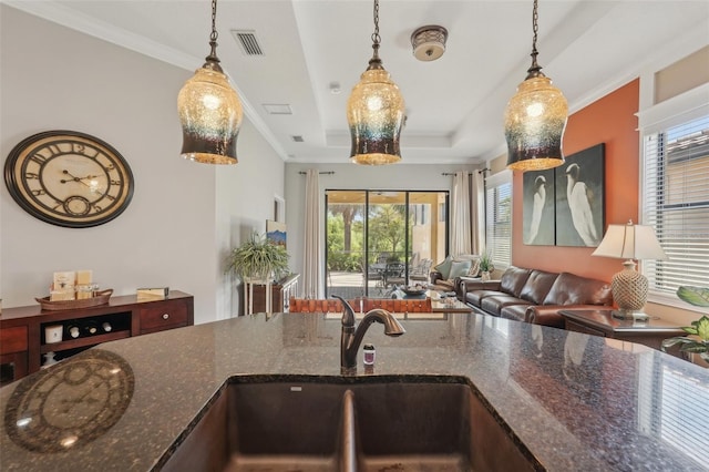 kitchen with crown molding, a sink, open floor plan, visible vents, and a healthy amount of sunlight
