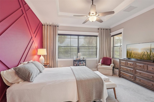bedroom with crown molding, a tray ceiling, visible vents, a ceiling fan, and light carpet