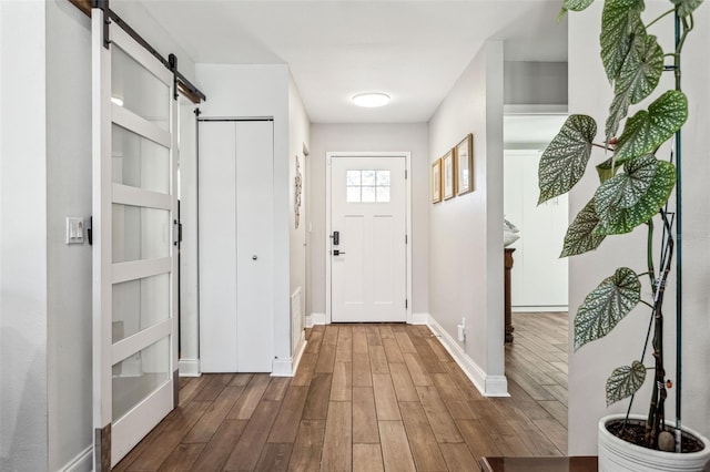 doorway to outside featuring a barn door, wood finished floors, and baseboards