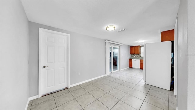 empty room with light tile patterned floors, visible vents, and baseboards