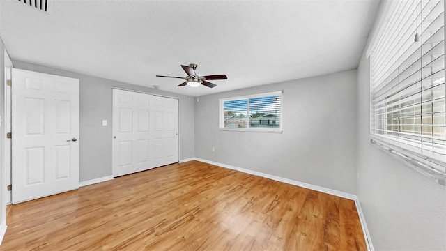 unfurnished bedroom featuring a ceiling fan, baseboards, visible vents, light wood-style flooring, and a closet