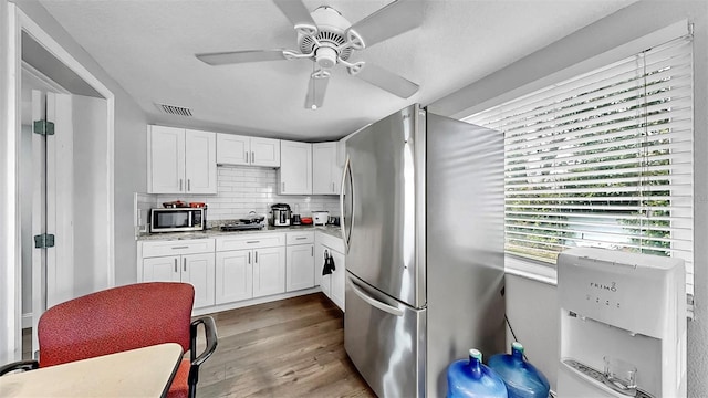 kitchen featuring wood finished floors, visible vents, ceiling fan, appliances with stainless steel finishes, and white cabinetry