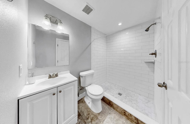 bathroom with visible vents, toilet, vanity, and tiled shower