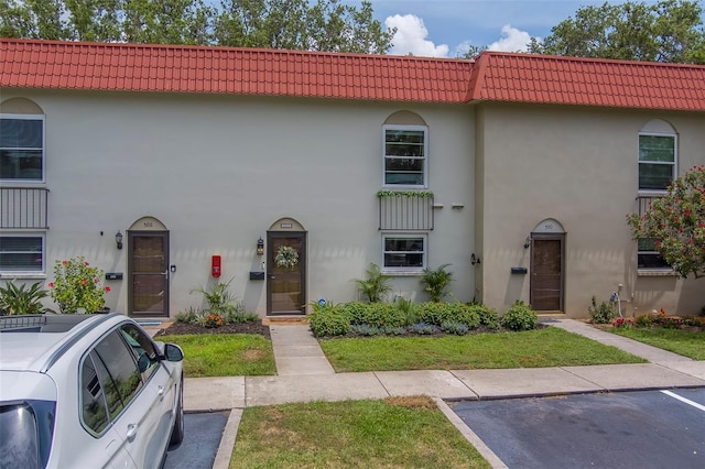 2700 Bayshore Blvd Unit 588, Dunedin, FL 34698 - view of front facade featuring stucco siding, a tile roof, and uncovered parking