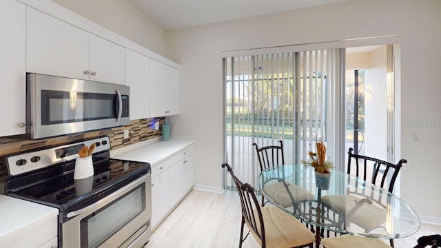 11822 Crawford Parrish Ln, Parrish, FL 34219 - kitchen with stainless steel appliances, decorative backsplash, white cabinetry, light countertops, and light wood-type flooring