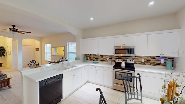 11822 Crawford Parrish Ln, Parrish, FL 34219 - kitchen featuring appliances with stainless steel finishes, arched walkways, tasteful backsplash, a peninsula, and light countertops
