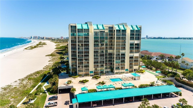 view of apartment building / complex featuring view of water and beach and a parking lot