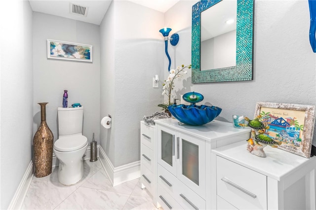 bathroom with marble finish flooring, toilet, baseboards, and vanity