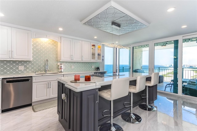 kitchen with stainless steel dishwasher, a sink, light countertops, tasteful backsplash, and recessed lighting