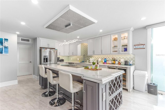 kitchen with high quality fridge, light marble finish flooring, tasteful backsplash, a center island, and recessed lighting
