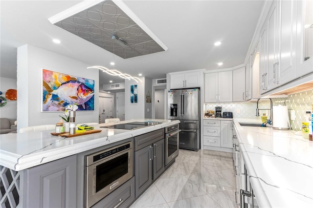 kitchen featuring stainless steel appliances, a sink, recessed lighting, white cabinets, and backsplash
