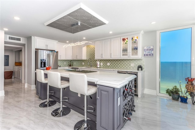 kitchen featuring light marble finish flooring, backsplash, high end fridge, a sink, and recessed lighting