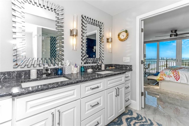 bathroom featuring connected bathroom, double vanity, a ceiling fan, and a water view