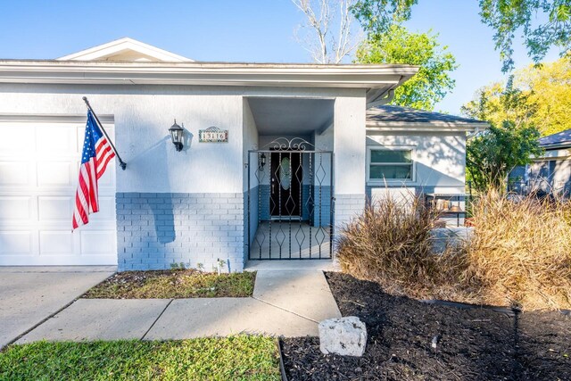 doorway to property with a garage and brick siding