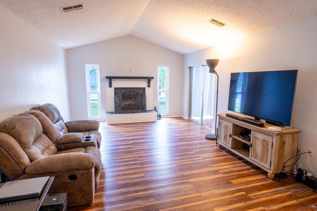 living room with vaulted ceiling, visible vents, a healthy amount of sunlight, and wood finished floors