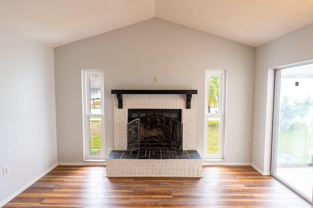 unfurnished living room featuring baseboards, lofted ceiling, wood finished floors, and a fireplace