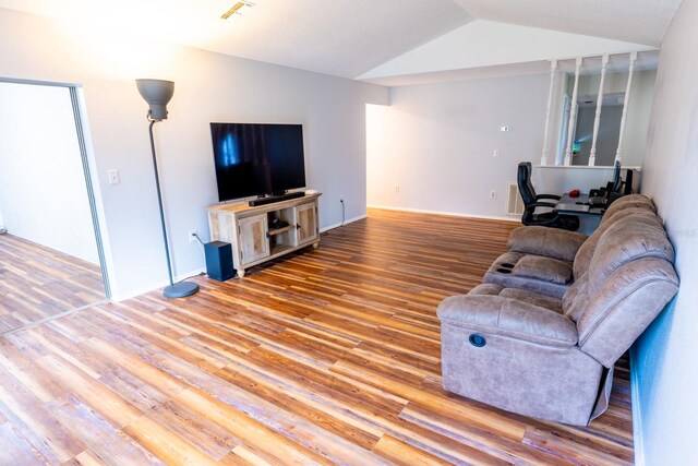 living area with baseboards, lofted ceiling, and wood finished floors