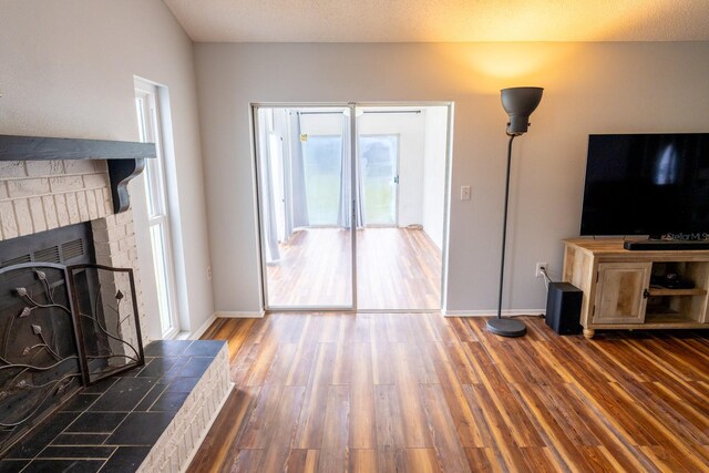 unfurnished living room featuring baseboards, wood finished floors, and a fireplace