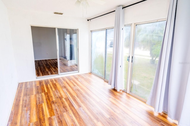 spare room featuring a ceiling fan, wood finished floors, and visible vents