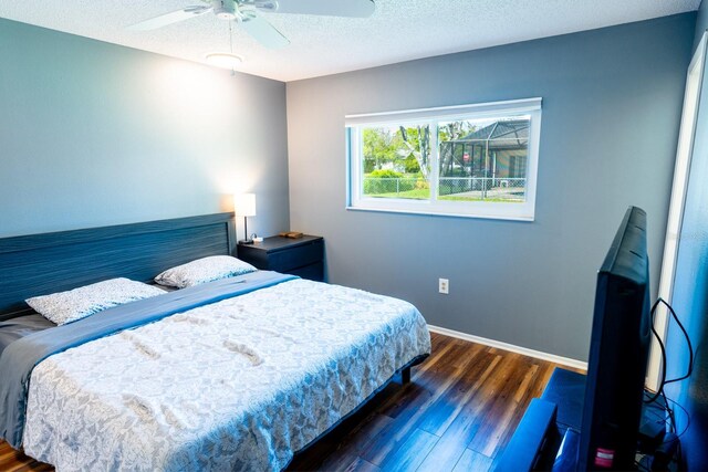 bedroom with a ceiling fan, wood finished floors, baseboards, and a textured ceiling