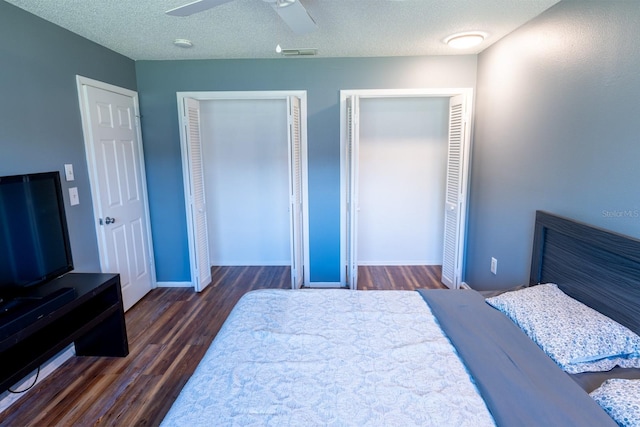 bedroom with multiple closets, wood finished floors, visible vents, and a textured ceiling
