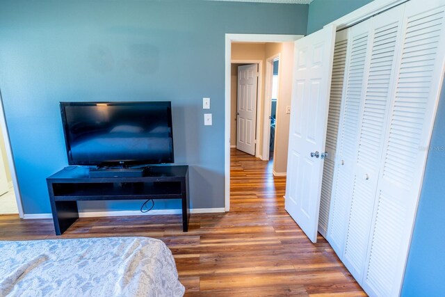 bedroom featuring wood finished floors, a closet, and baseboards