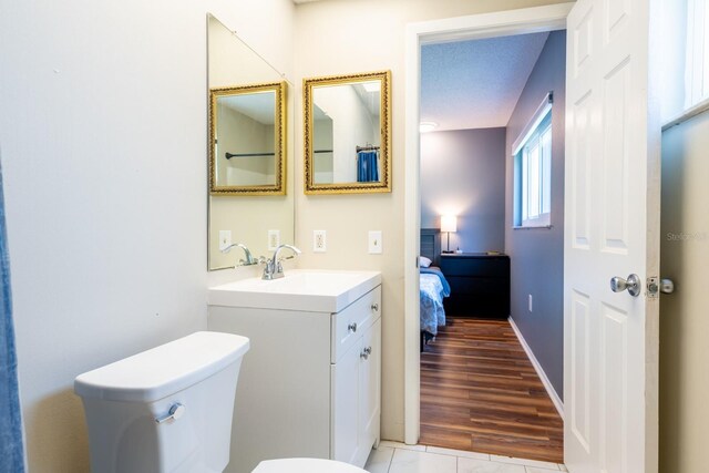 bathroom featuring toilet, wood finished floors, and vanity