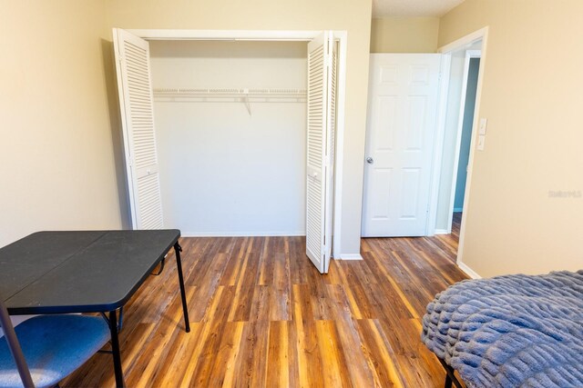 bedroom featuring a closet, baseboards, and wood finished floors