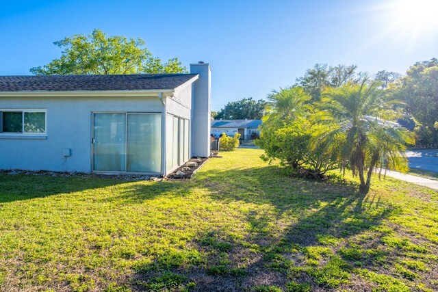 exterior space with stucco siding, a lawn, and a chimney