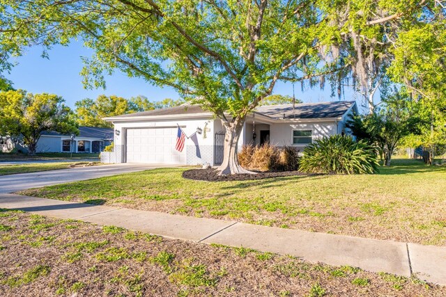 ranch-style home with stucco siding, driveway, a front lawn, and a garage