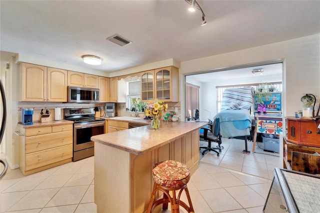2533 Limewood Dr, Holiday, FL 34690 - kitchen with stainless steel appliances, light brown cabinetry, a kitchen breakfast bar, glass insert cabinets, and a peninsula