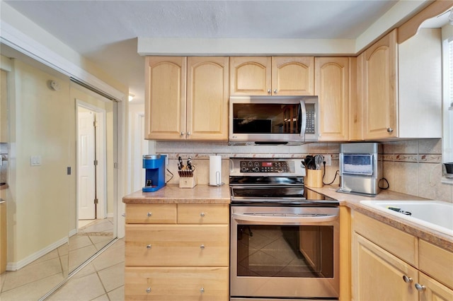 2533 Limewood Dr, Holiday, FL 34690 - kitchen featuring appliances with stainless steel finishes, light brown cabinets, tasteful backsplash, light tile patterned floors, and light countertops
