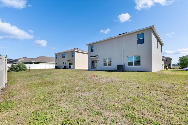 back of house featuring fence, stucco siding, a lawn, and central air condition unit