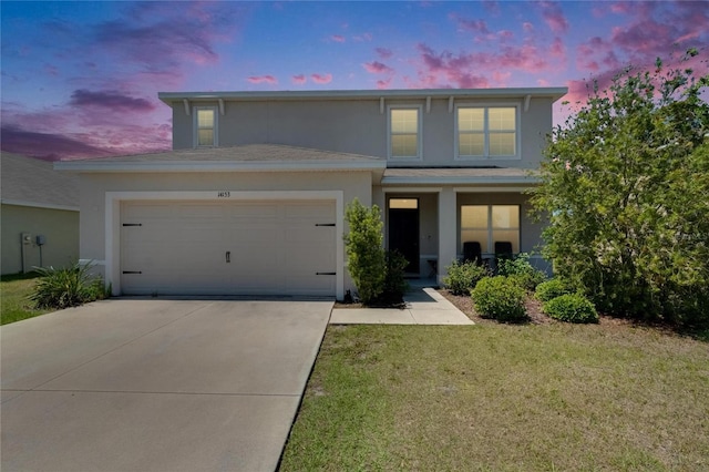 traditional home featuring a yard, driveway, stucco siding, and an attached garage